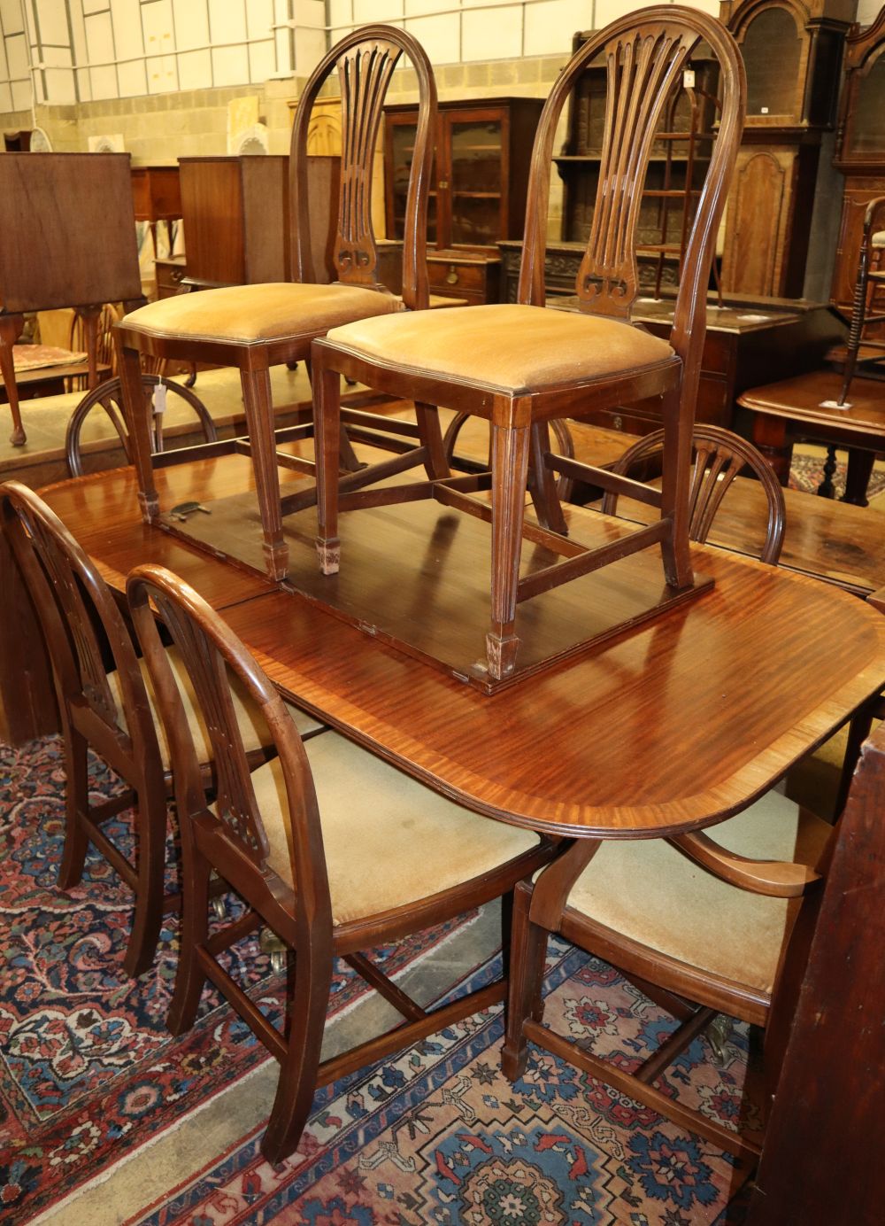 A set of eight Hepplewhite style mahogany dining chairs (two with arms), together with a George III style mahogany twin pillar extendin